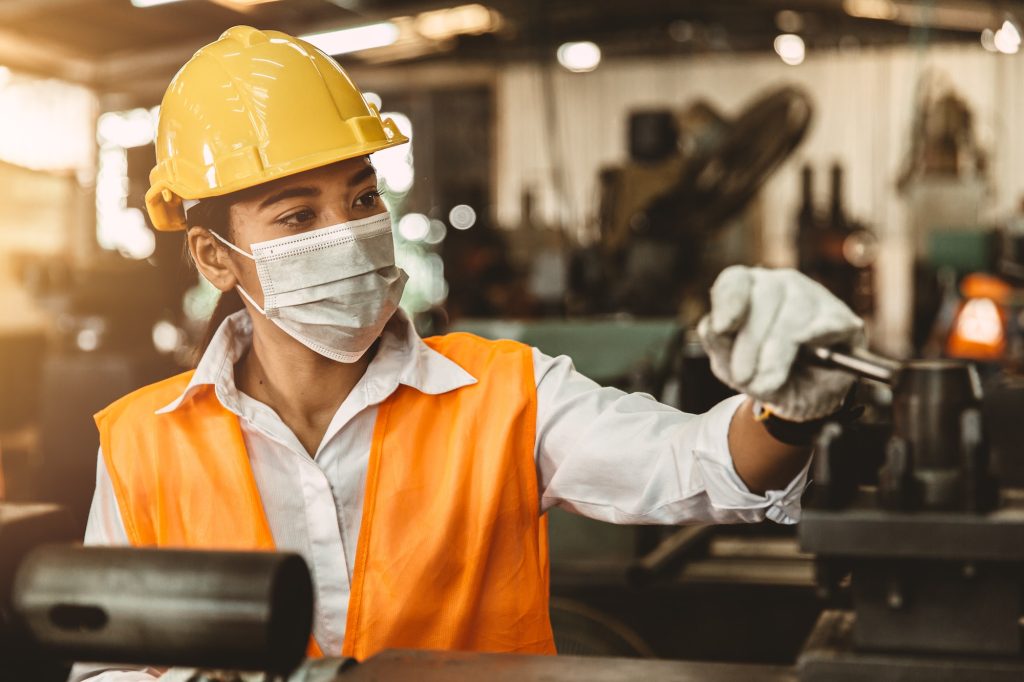 Asian Woman Worker with Safety Helmet and Face Mask Working as Labor in Heavy Industry Factory.