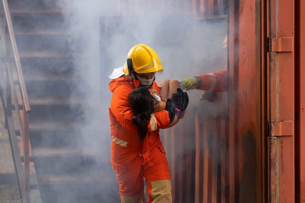 Fire fighting team rescue life saving young girl from fire burn and handover child through window