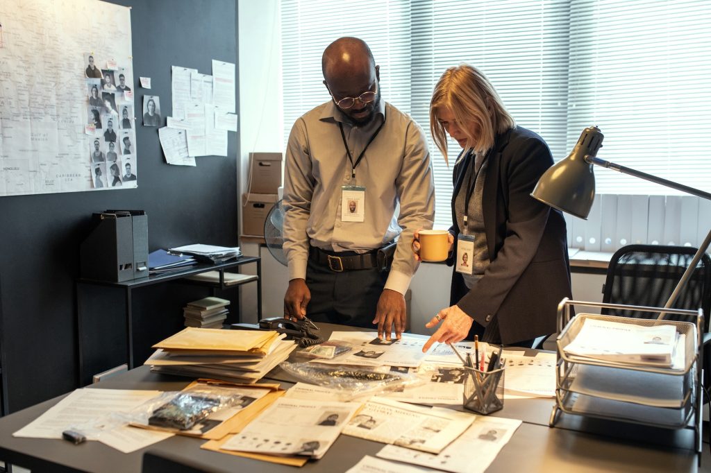 Two intercultural investigators in formalwear discussing personal information